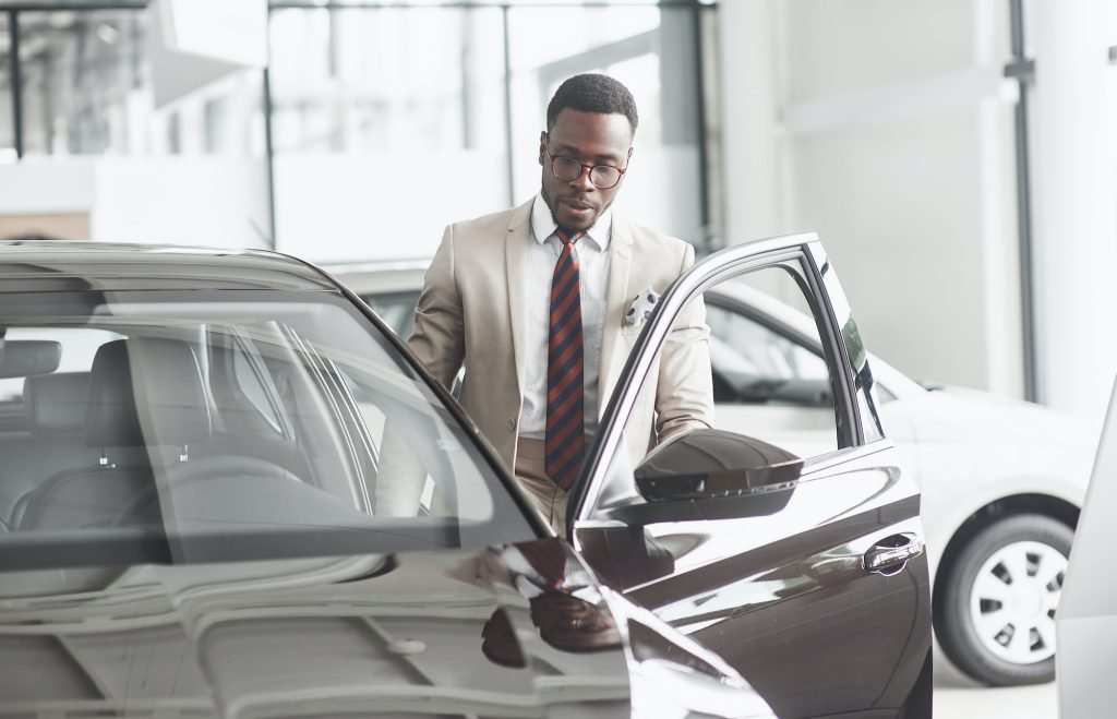 An African American inspects the car at the car dealership. Good bargain
